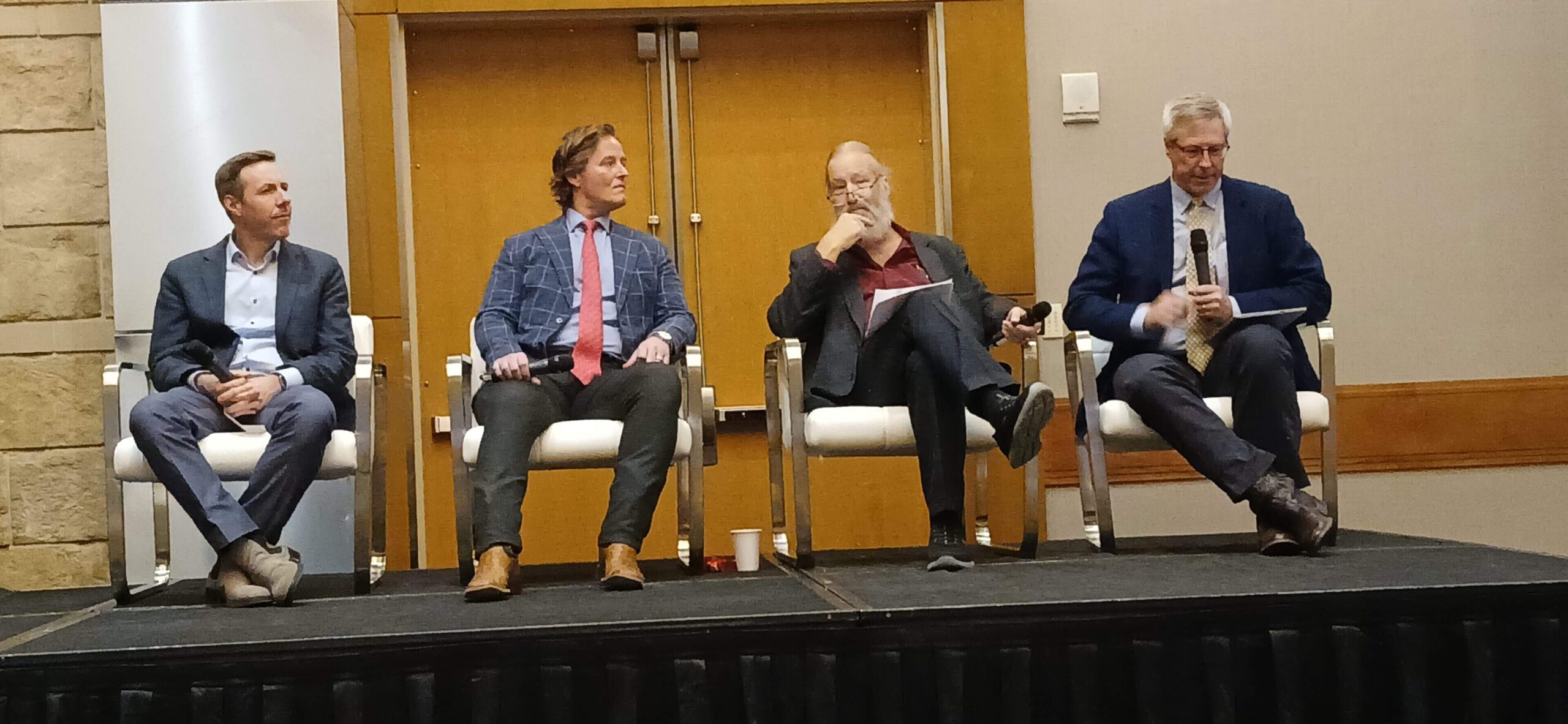 Two men sitting on stage chairs during a panel discussion.