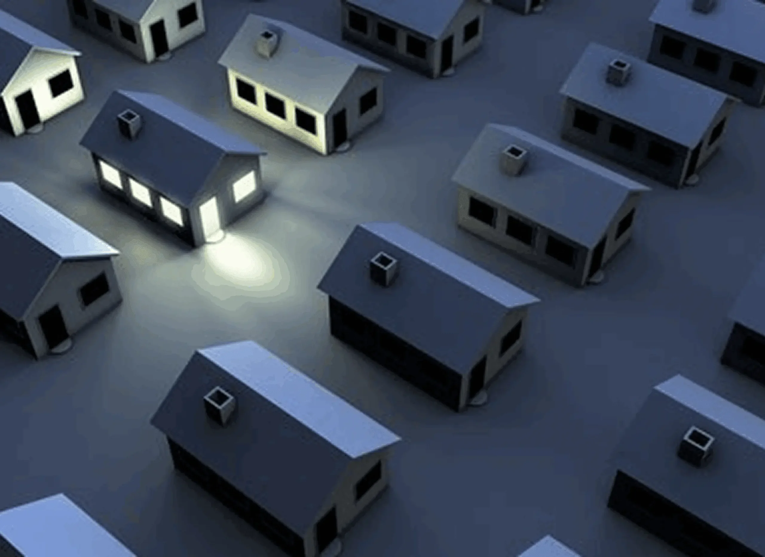 A nighttime scene showing houses with illuminated windows and streetlights.